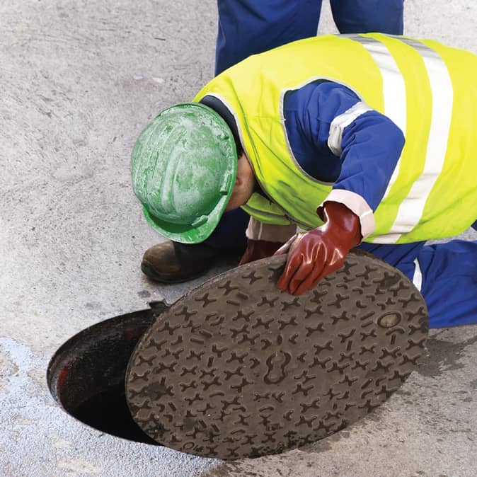 worker opening sewer manhole cover